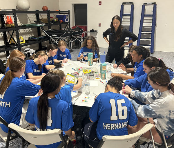 Sabrina leading a team activity as players work together around a table
